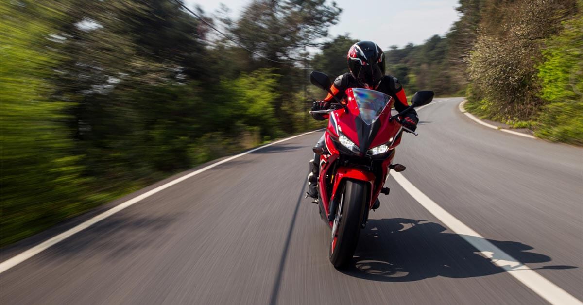 Una persona montando una motocicleta roja
en una carretera.
