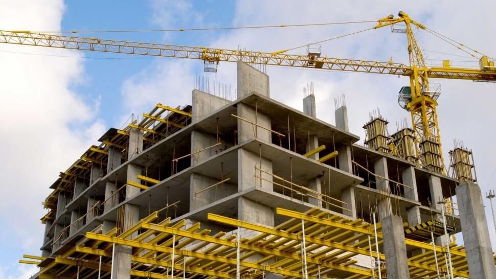 Grúa de construcción erguida sobre un edificio
en construcción, simbolizando el avance de la
obra arquitectónica.