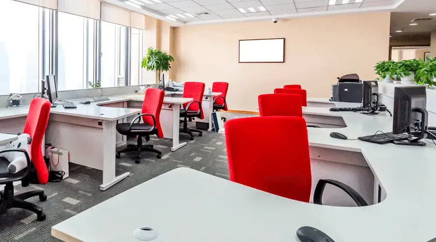 Oficina con sillas rojas y escritorios blancos,
creando un ambiente moderno y profesional.