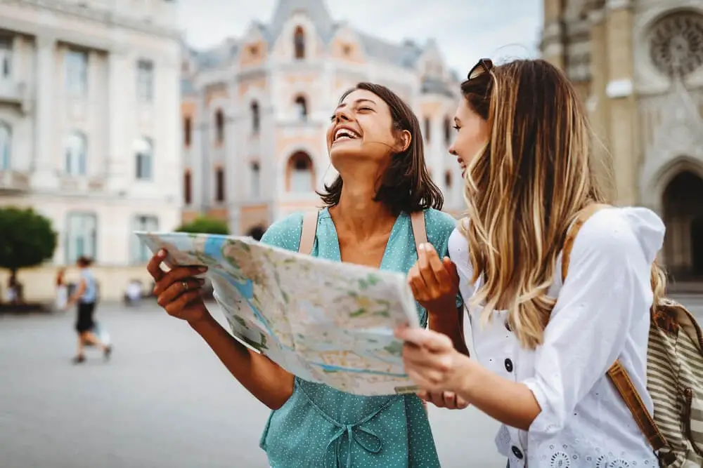 Dos mujeres turistas riendo y sosteniendo un mapa