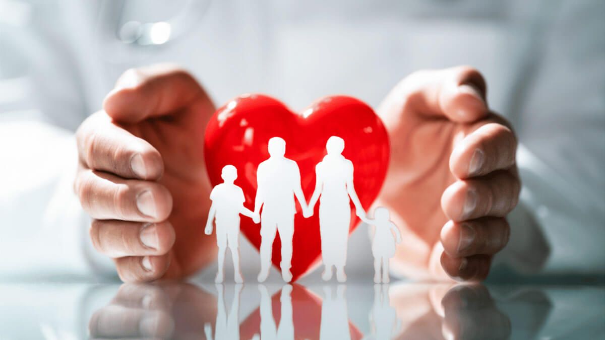 Un médico muestra un corazón de caricatura
y un recorte en papel de una familia unida.